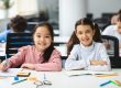 Portrait of small girls sitting at desk in classroom